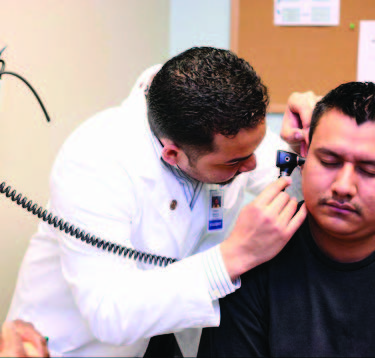  a doctor looks into a man's ear using an instrument